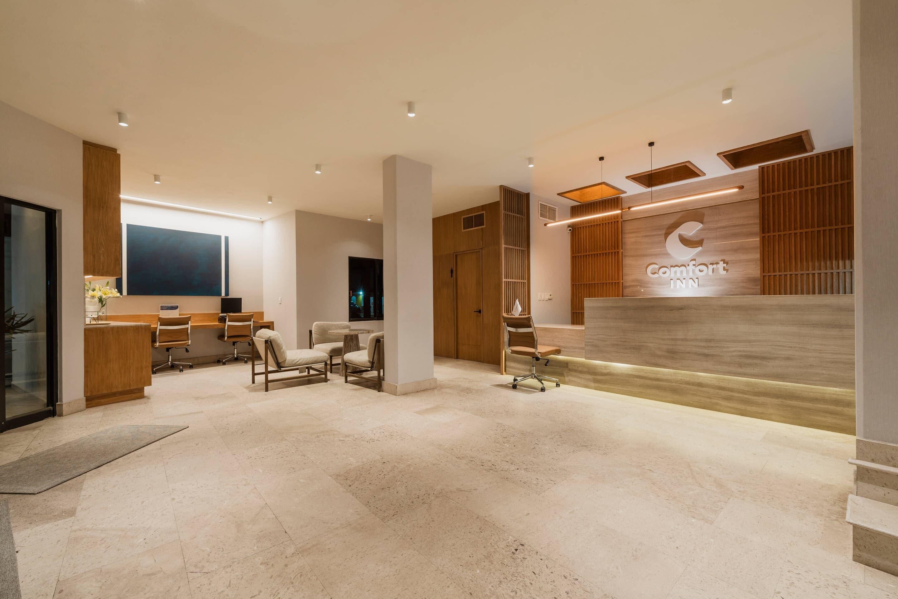 A modern hotel lobby with a reception desk, seating area, and a large wall with the hotel name.