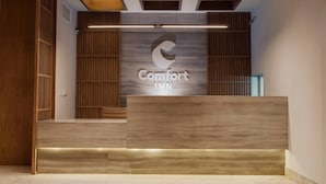 A reception desk with a logo, wooden paneling, and a modern design. - Comfort Inn Tampico (Tampico)