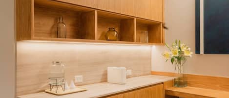 Una cocina con armarios de madera, una encimera, un frasco de vidrio, un tostador y un jarrón con flores.