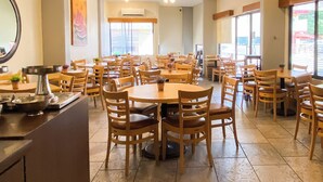 A spacious dining area with multiple wooden tables and chairs, ceiling fans, and large windows allowing natural light. - Comfort Inn Tampico (Tampico)