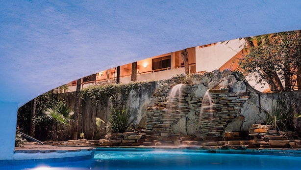 A pool with a waterfall feature, a stone wall, and a building with balconies. - Comfort Inn Tampico (Tampico)