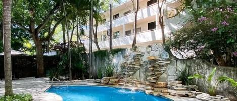 A swimming pool surrounded by lush greenery and a stone wall.
