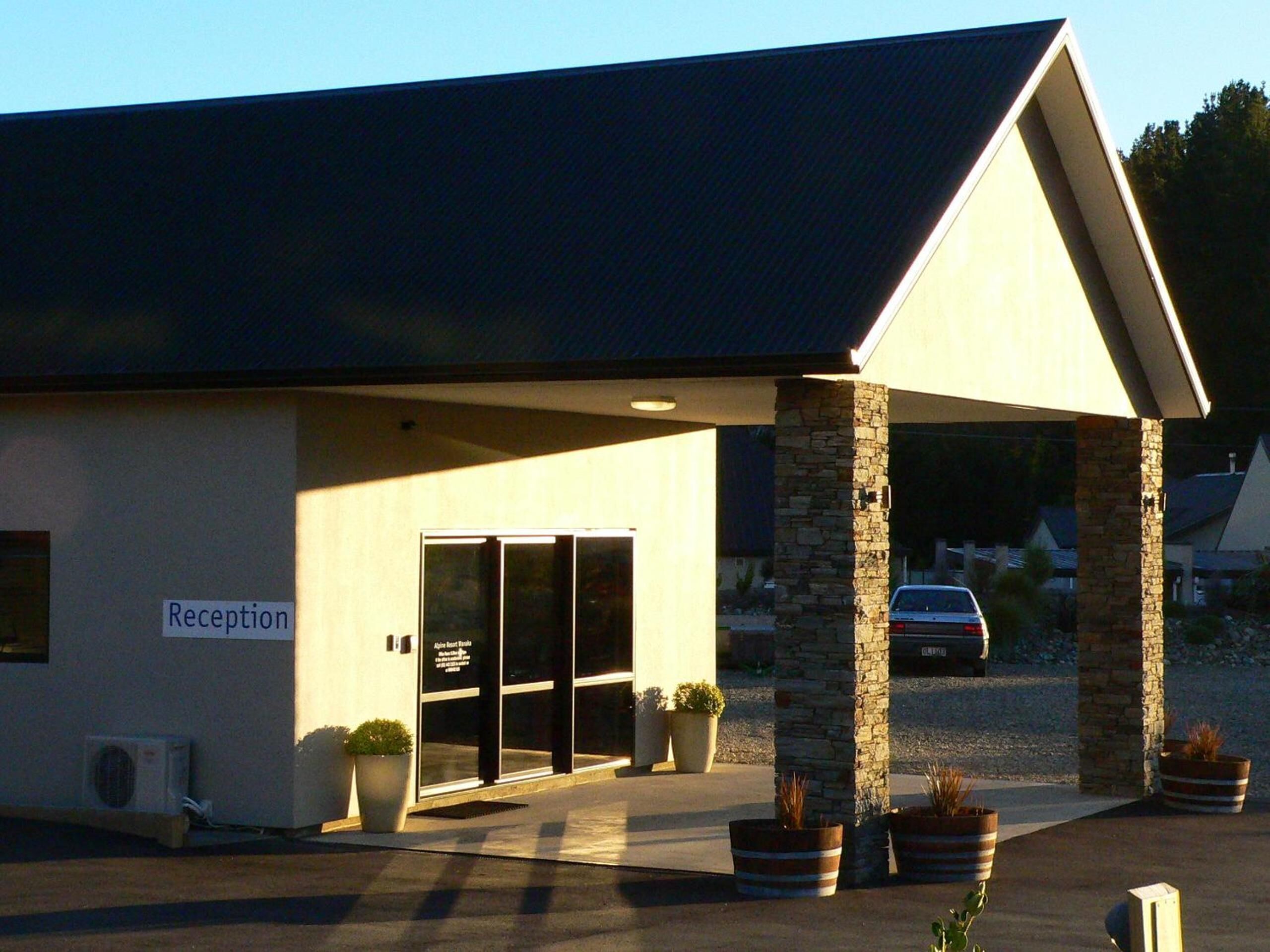 A building with a reception area, large windows, and potted plants.