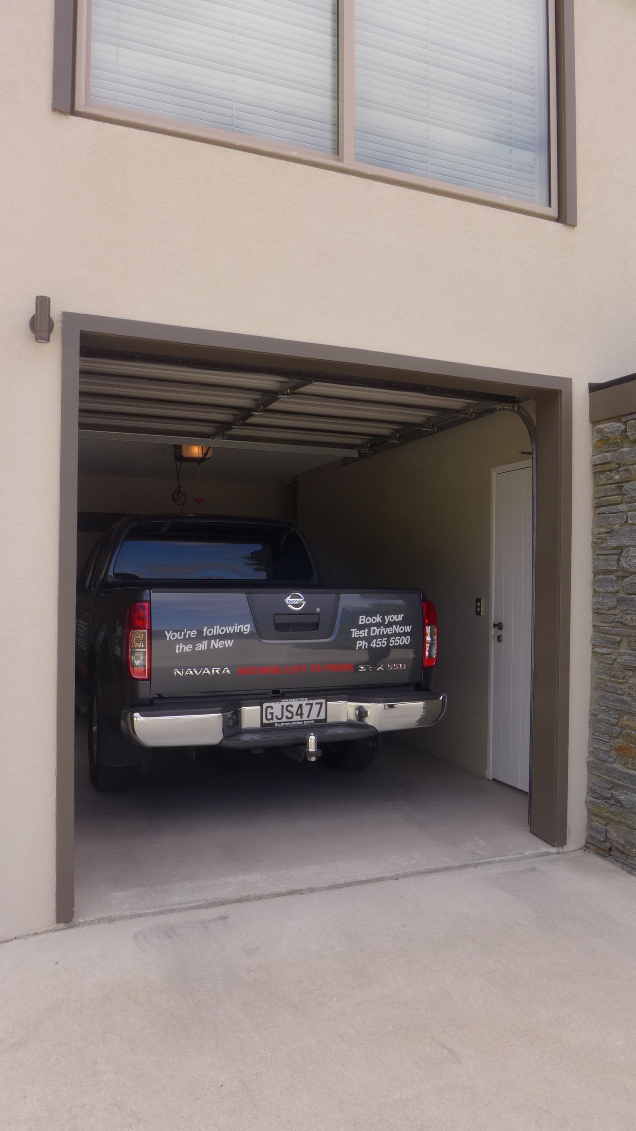 Ein schwarzer Nissan-Truck steht in einer Garage, auf der Heckscheibe ist ein Schild mit dem Schriftzug 'Book your Test DriveNow' zu sehen.