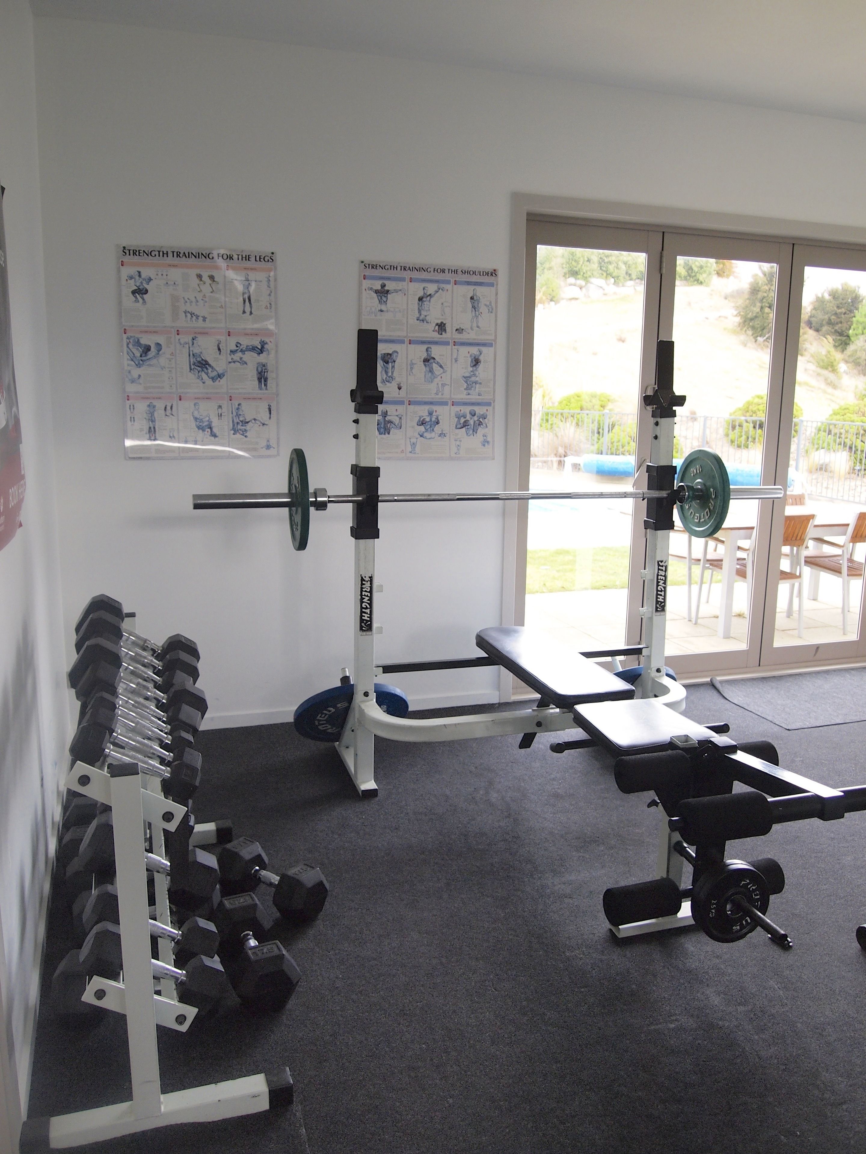 A gym with weightlifting equipment, including dumbbells and a bench press.