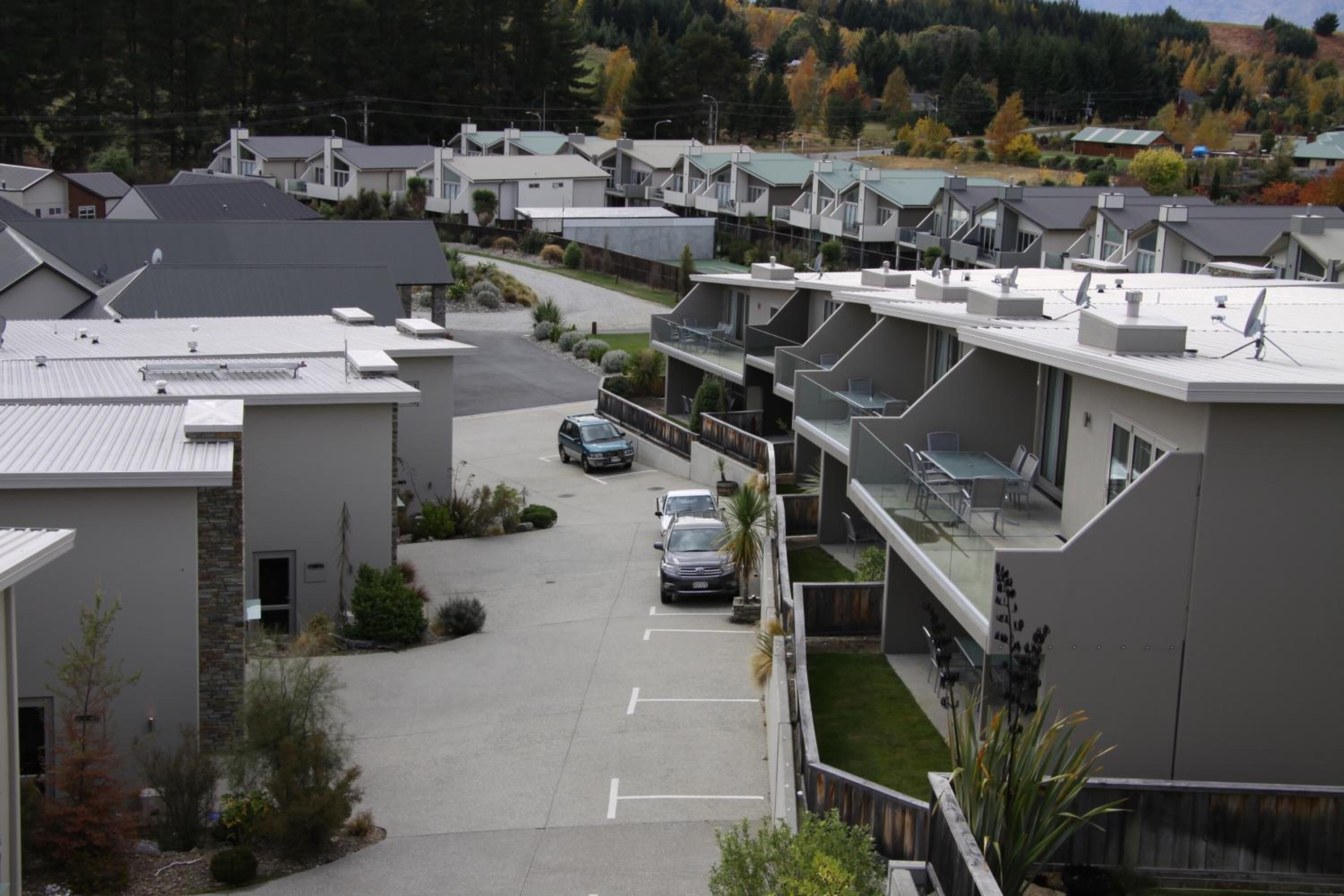 Un área residencial moderna con casas independientes, un camino central y un estacionamiento.