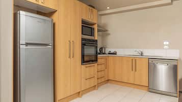 Eine moderne Küche mit Holzausbau, einem Edelstahlkühlschrank, einem Backofen, einer Mikrowelle und einem Geschirrspüler.