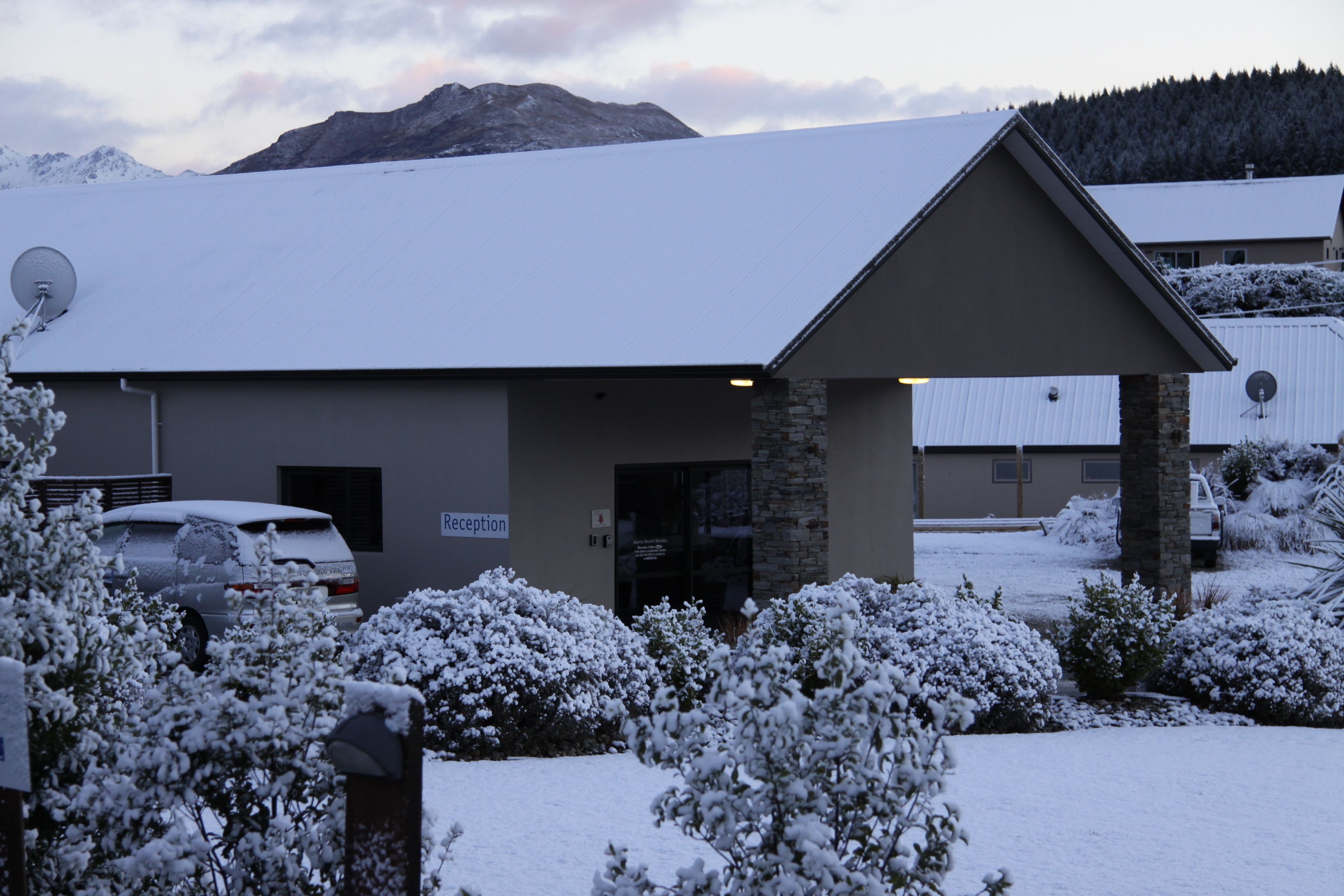 A building with a reception area, snow-covered surroundings, and a mountain in the background.