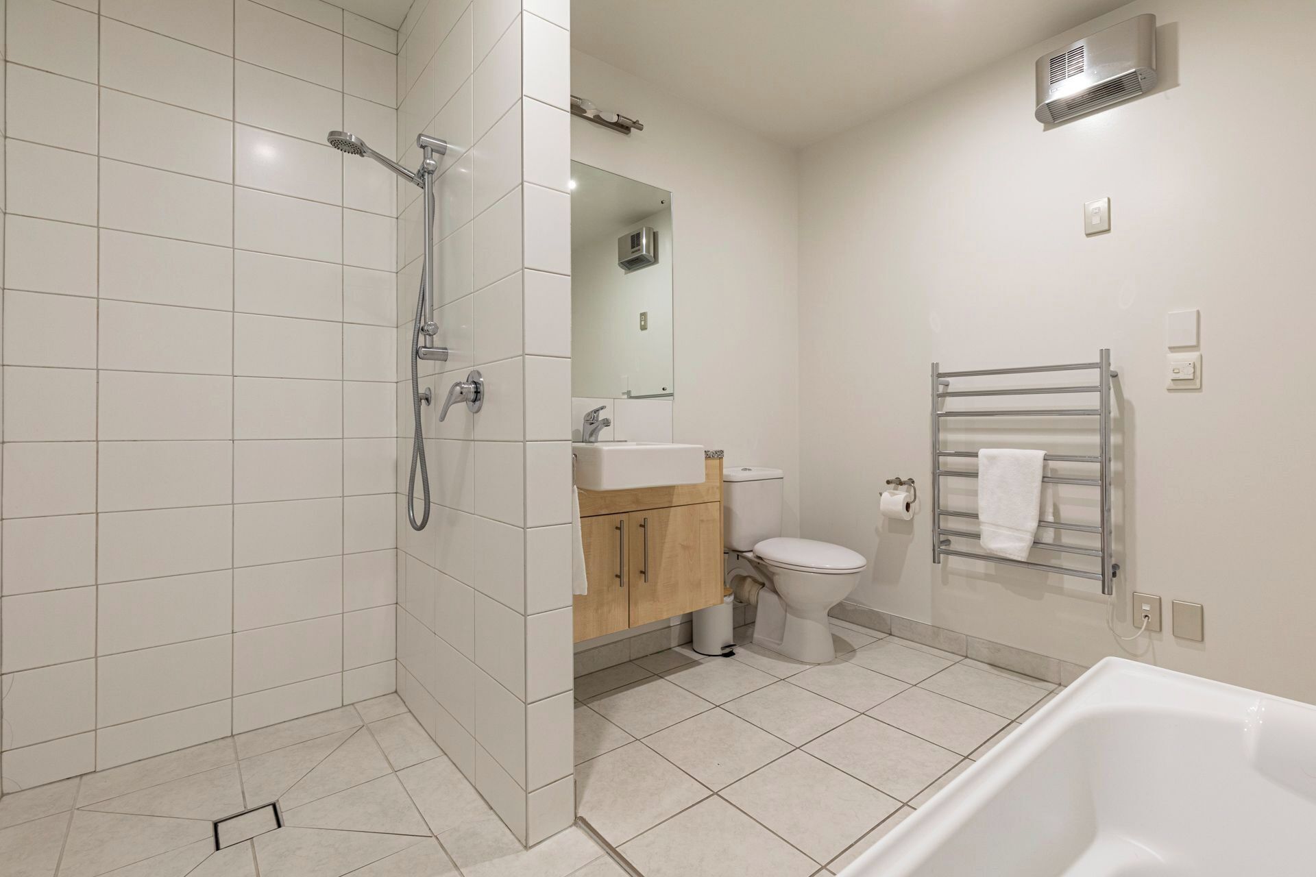 A modern bathroom with a shower, toilet, sink, and bathtub.