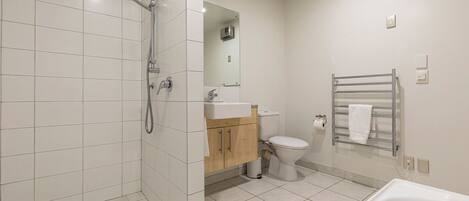 A modern bathroom with a shower, toilet, sink, and bathtub.