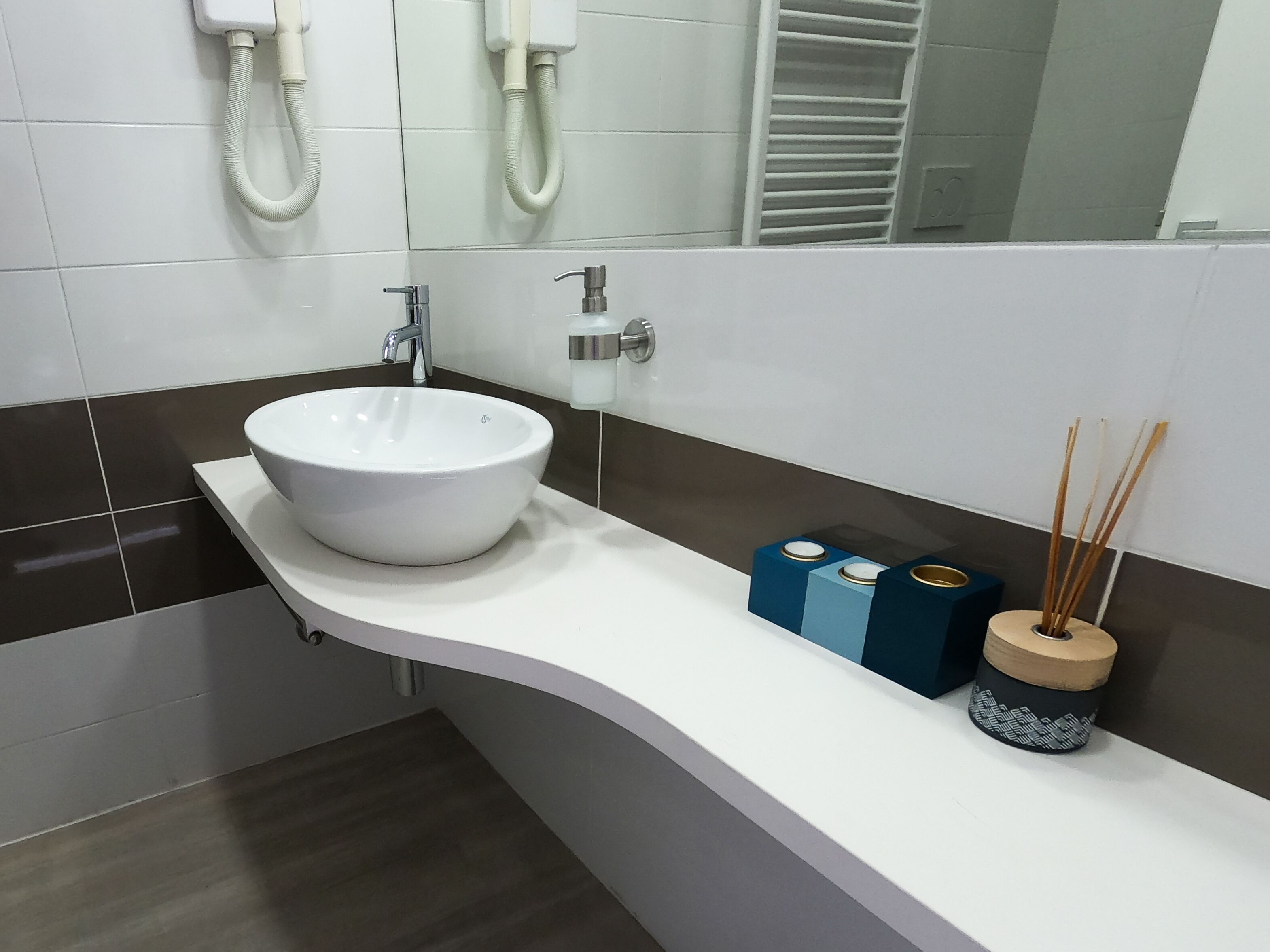 A modern bathroom with a white sink, a mirror, and a towel rack.