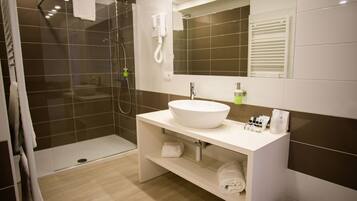 Une salle de bain moderne avec une douche à parois de verre, un lavabo blanc et un miroir au-dessus.