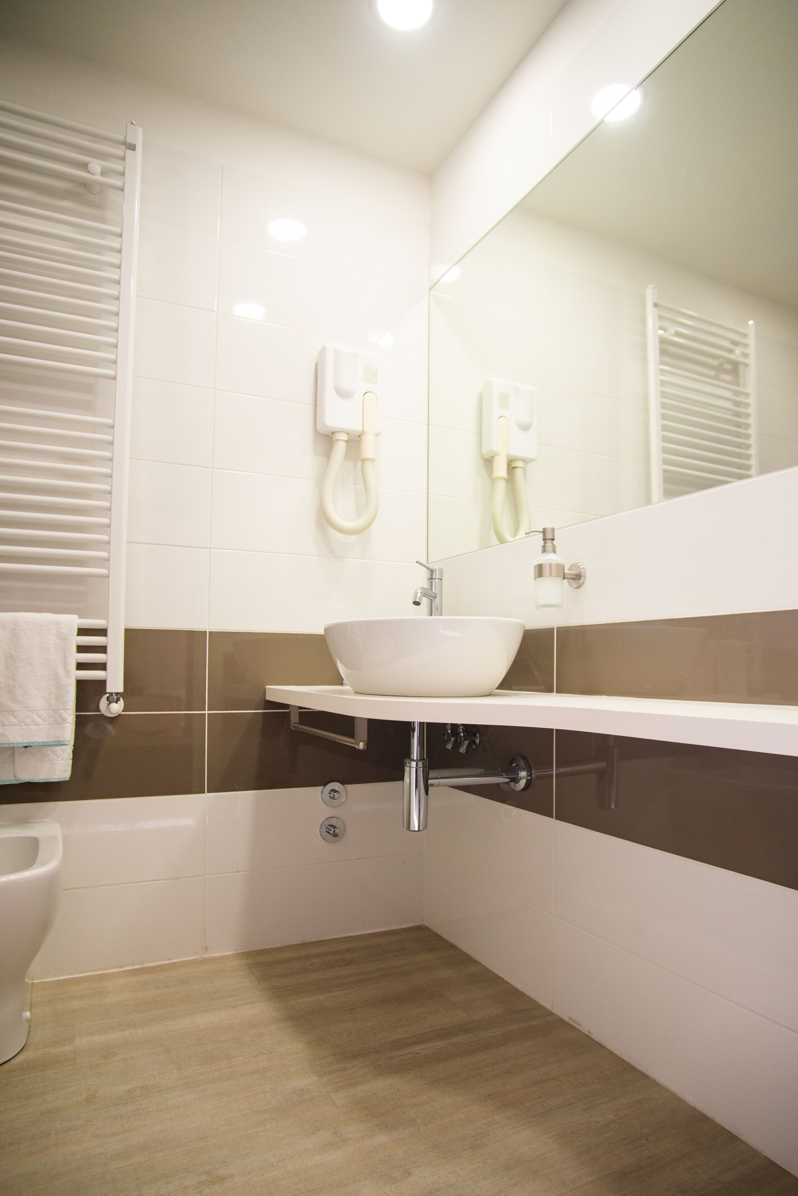 Une salle de bain avec un lavabo blanc, un miroir, un porte-serviettes et des toilettes.