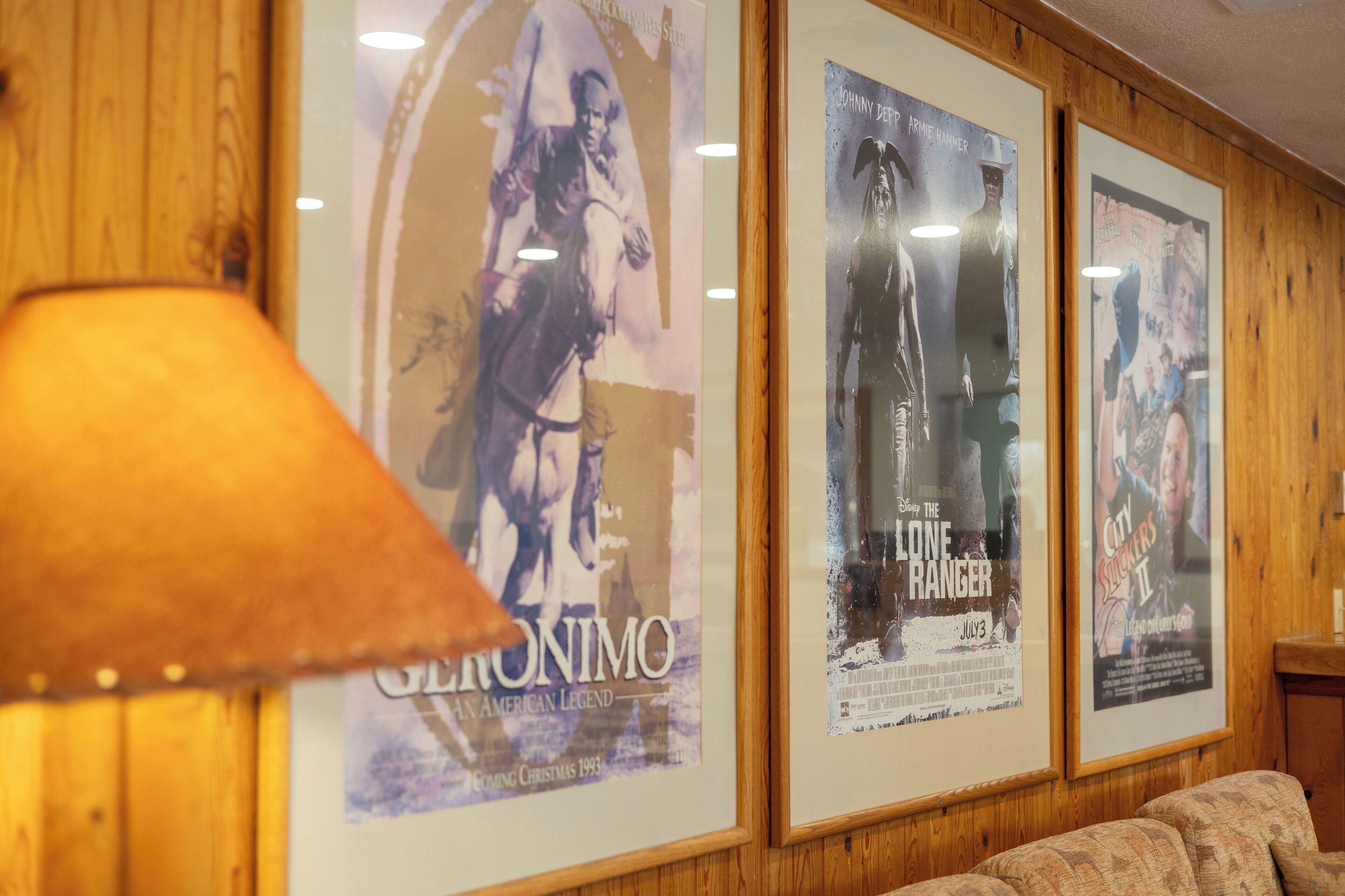 Framed movie posters on a wall with a lamp in the foreground.