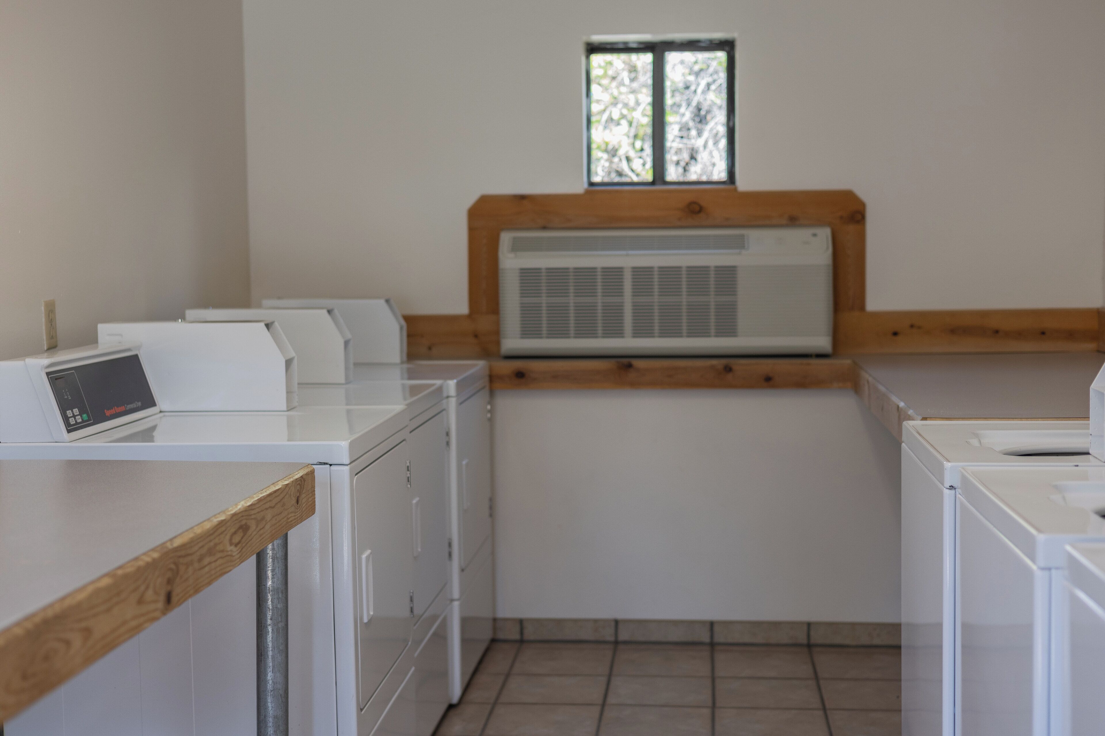A laundry room with stacked dryers, a washing machine, and a control panel.