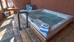 A wooden spa tub with a towel, a caution sign, and a window.