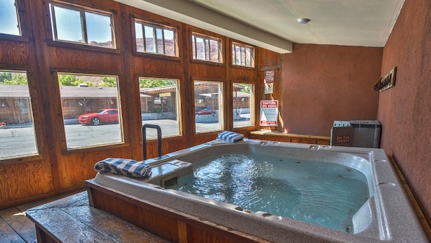 A wooden spa room with a hot tub, wooden benches, and large windows.