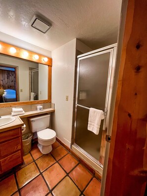 Une salle de bain équipée de toilettes, d’un lavabo, d’un miroir et d’une douche.