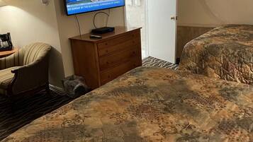 A hotel room with a bed, a television, a wooden dresser, a chair, and a door.