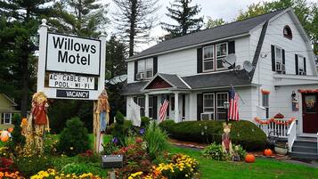 Casa blanca de dos pisos con un cartel que indica Motel Willows, que ofrece servicios como aire acondicionado, televisión por cable, piscina, Wi-Fi y televisión.