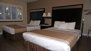 A hotel room with two beds, a nightstand with lamps, and a window with blinds. - Travelodge by Wyndham Concord (Concord)
