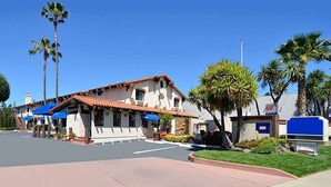 A two-story building with a red-tiled roof, a white facade, and a blue awning over the entrance. - Travelodge by Wyndham Concord (Concord)