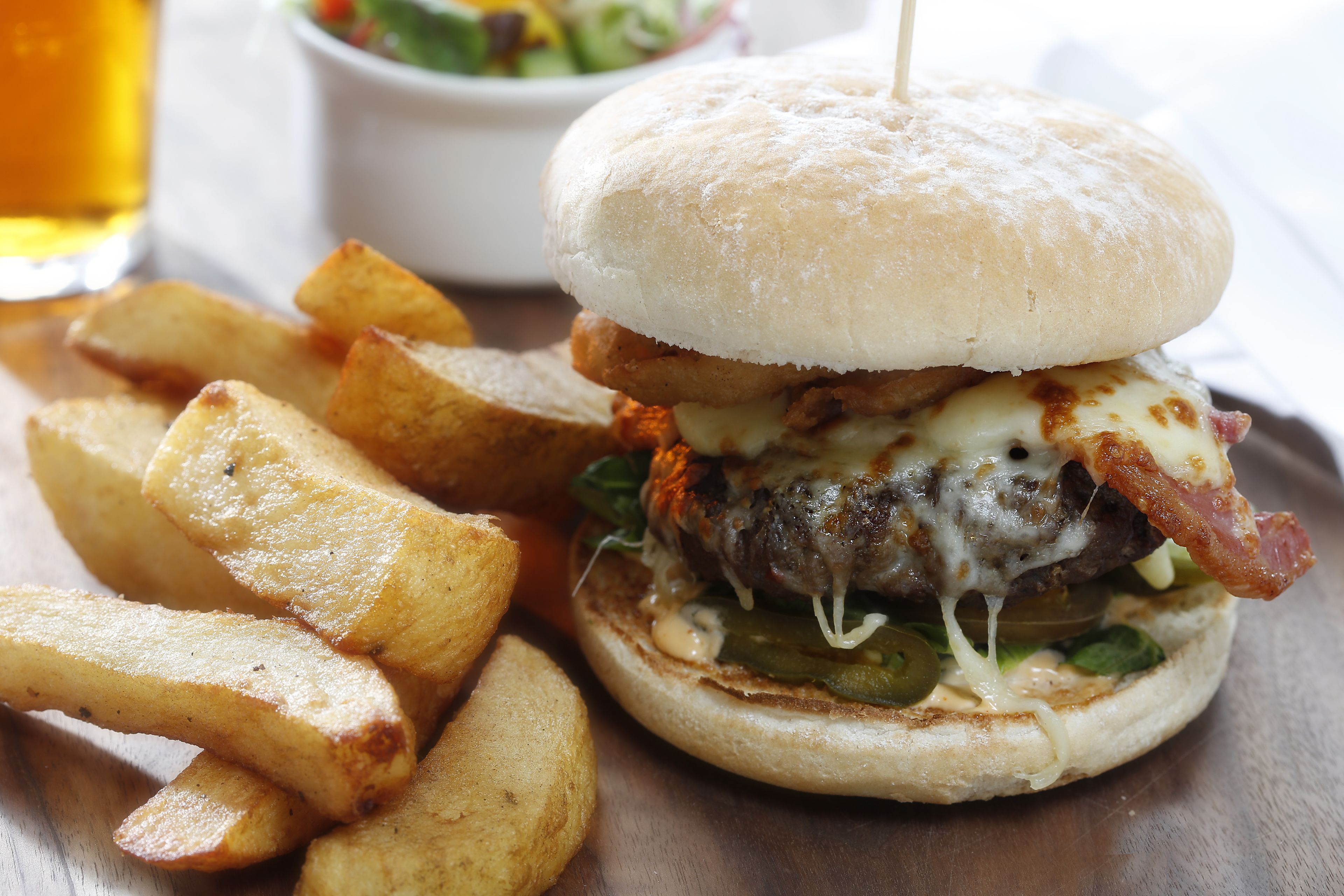 A burger with fries on a wooden table.