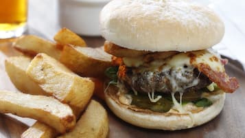 A burger with fries on a wooden table.