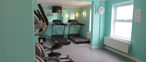 A gym with treadmills, stationary bikes, and a mirrored wall.