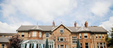 A large brick house with a conservatory, multiple windows, and outdoor seating.