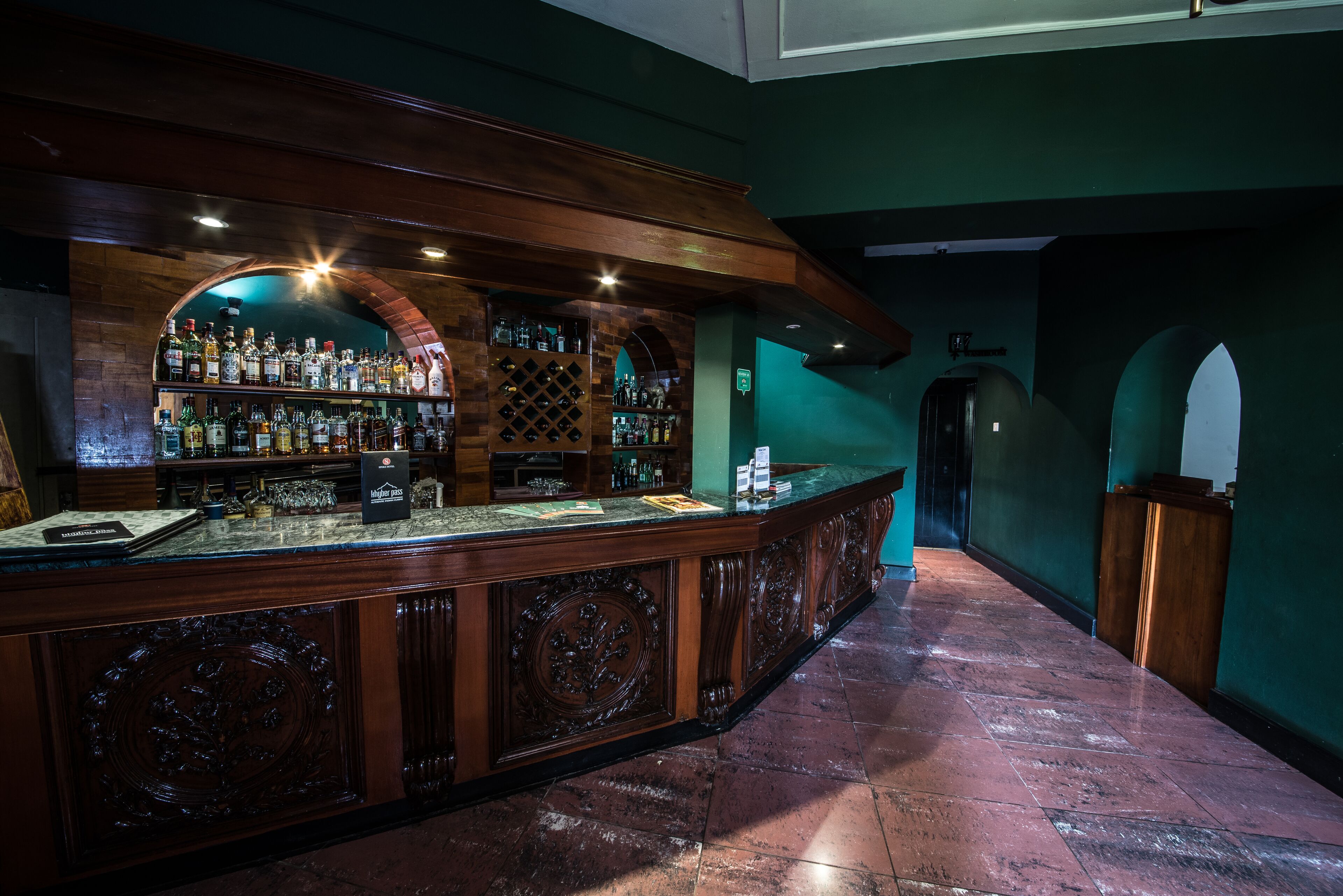 Un espace bar avec un comptoir en bois, des étagères remplies de bouteilles et un présentoir à vin.