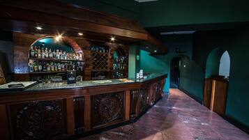 Un espace bar avec un comptoir en bois, des étagères remplies de bouteilles et un présentoir à vin.