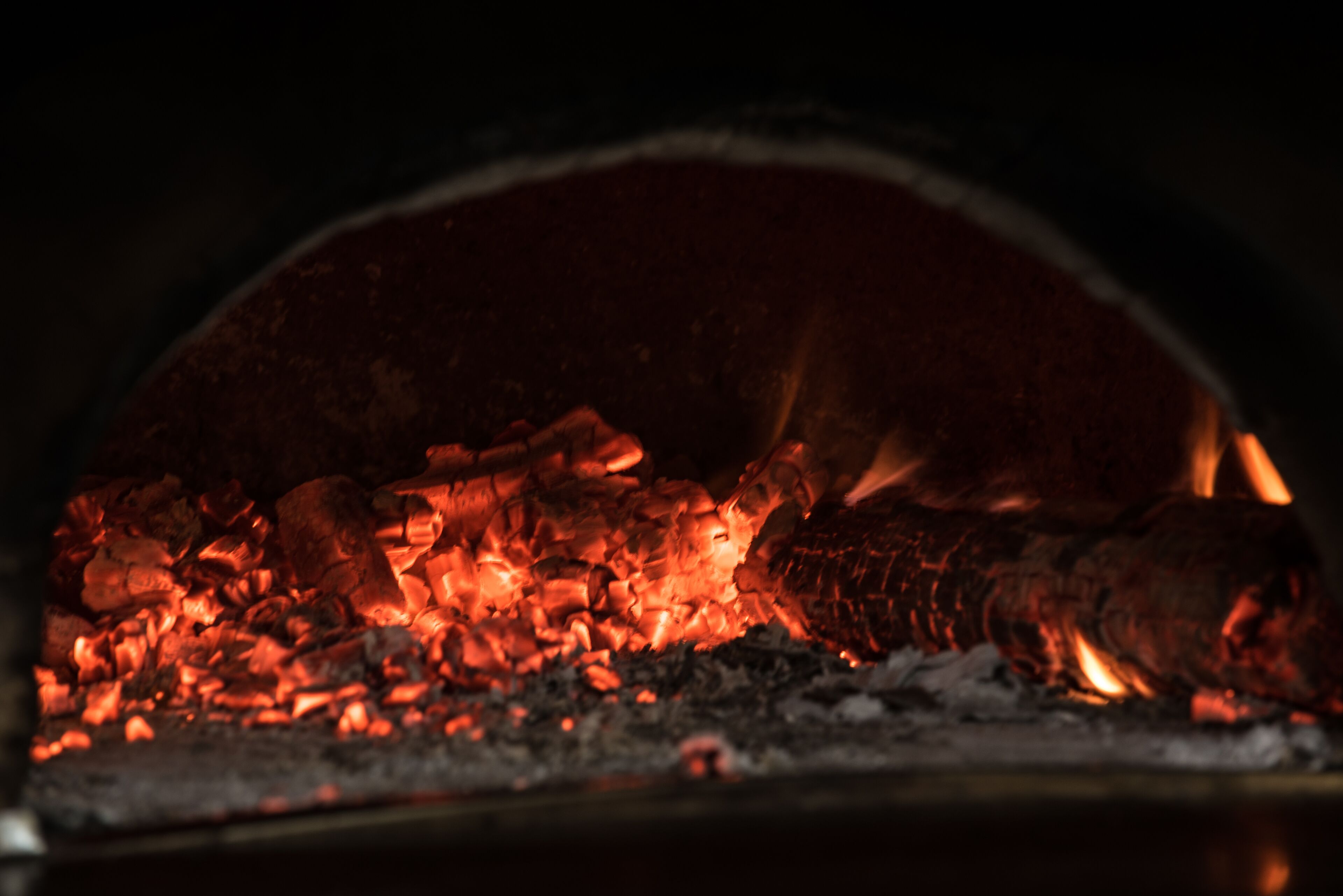A close-up of a wood-fired oven with glowing embers.