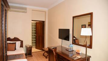 Une chambre d’hôtel comprenant un lit, une table de chevet, un bureau, une chaise et un grand miroir.