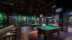 Sala de billar con varias mesas, una zona de bar y diversos banderines.