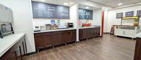 A bakery counter with a chalkboard menu, a coffee machine, and a microwave.