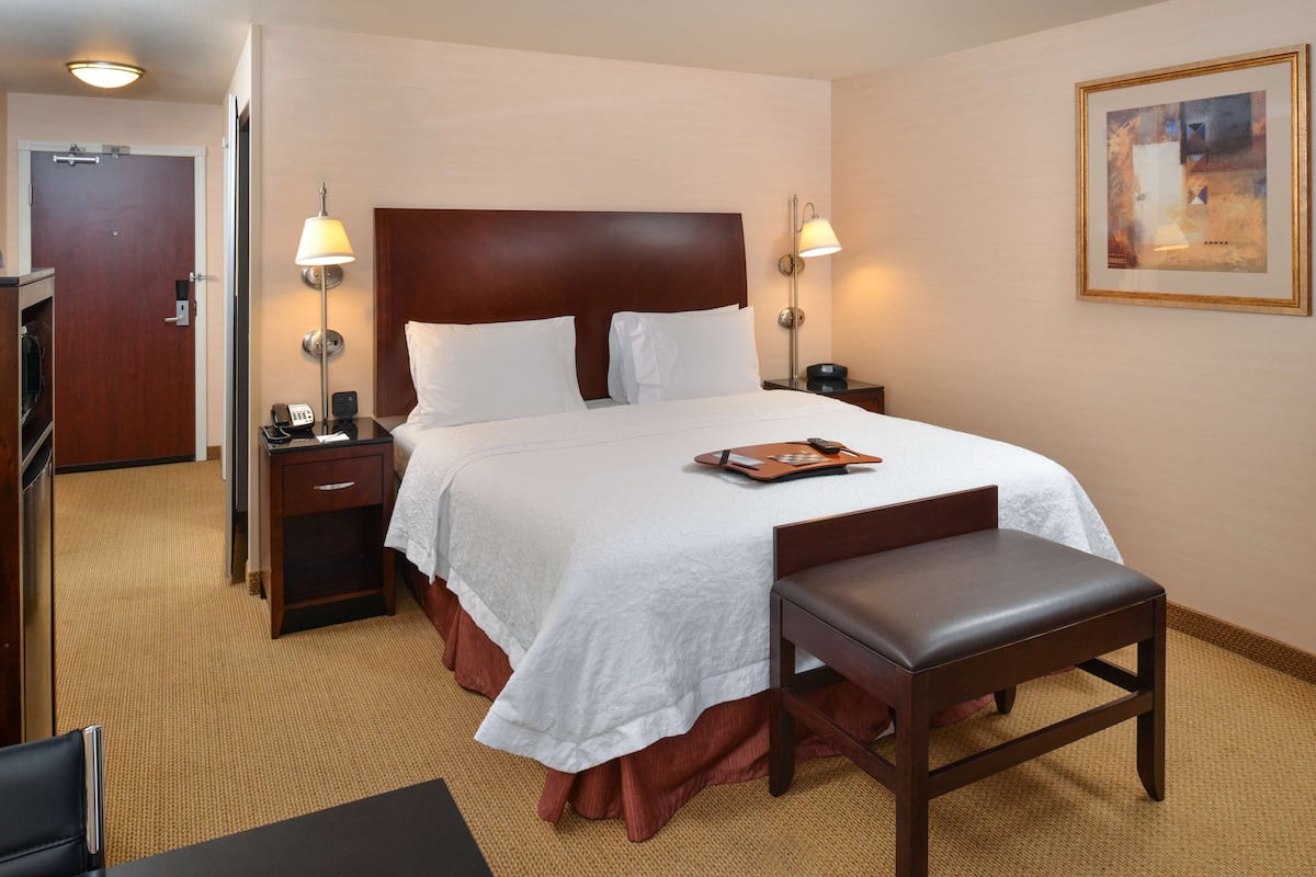 A hotel room with a large bed, two bedside tables, a desk, and a chair.