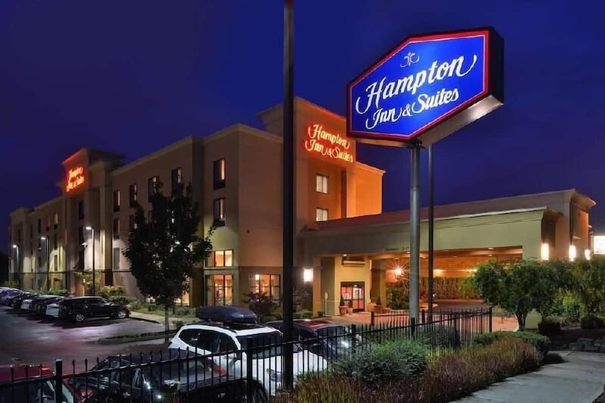 A hotel with a neon sign, a parking lot, and a well-lit entrance.