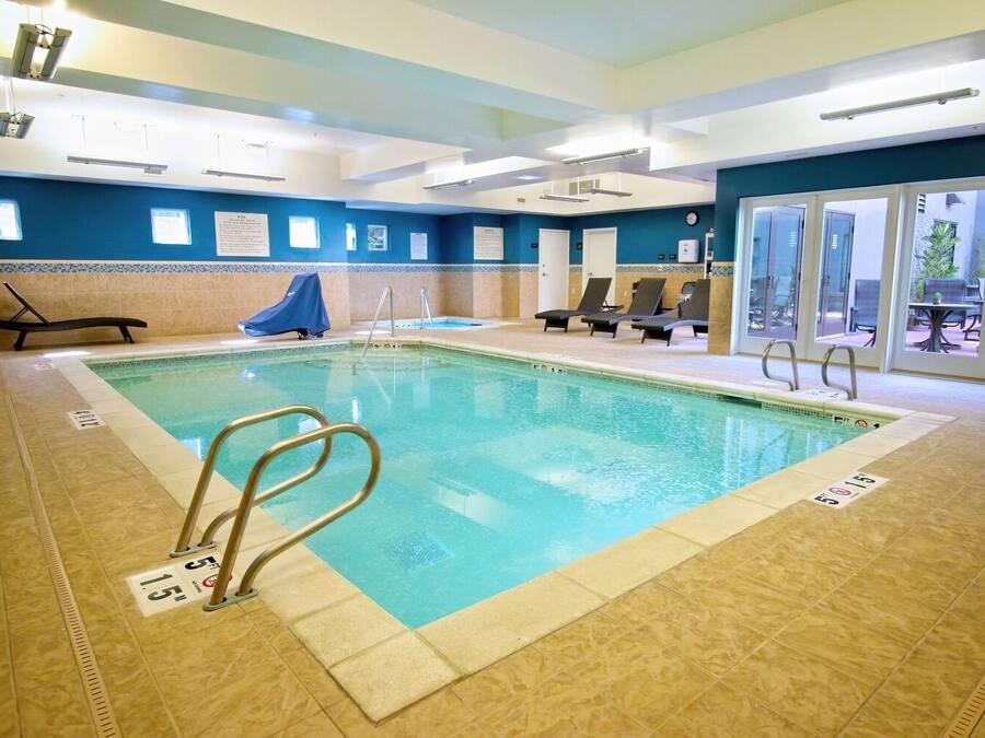 Una piscina interior con carriles claramente delimitados, sillones de descanso y una zona de estar techada.