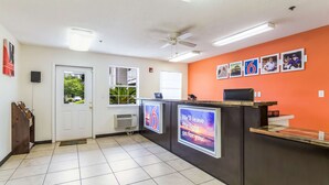 Un espace d’accueil comprenant un comptoir de réception, un ventilateur de plafond et un mur orné de tableaux.