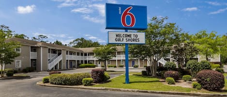 A motel sign with the number 6 and a welcome sign to Gulf Shores.