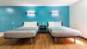 Une chambre double avec deux lits, une table de chevet et un luminaire fixé au mur.
