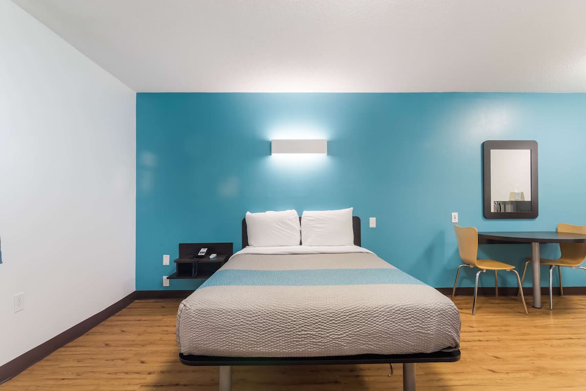 Une chambre d’hôtel avec un lit, un bureau et une chaise.