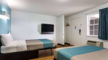 Habitación de hotel con dos camas, televisión, calefacción y ventana con cortinas.
