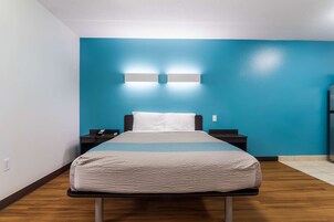 A hotel room with a bed, nightstands, a blue wall, and a wooden floor.