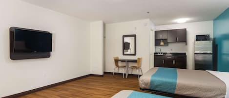 Ett hotellrum med två sängar, en TV, ett litet pentry och en matplats.