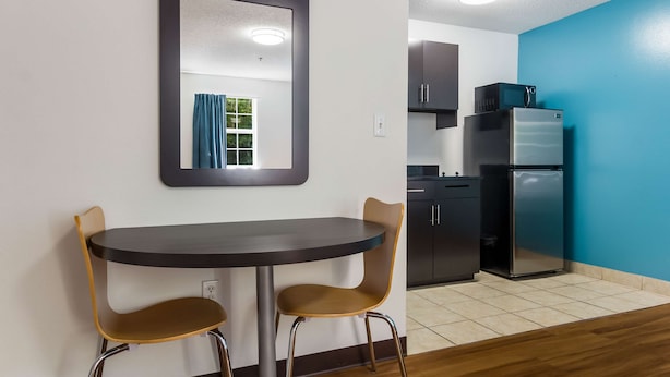 Une cuisine compacte dotée d’appareils électroménagers modernes, un coin repas avec deux chaises et un miroir au mur.