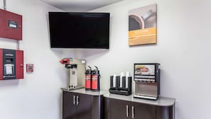 Une petite cuisine moderne équipée d’une machine à café, d’un distributeur de café et d’un espace dédié à la préparation et à la distribution de repas.