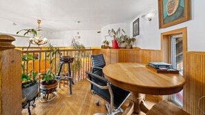 A wooden dining table with a chess book, surrounded by potted plants and black chairs. - Qupqugiaq Inn (Anchorage)