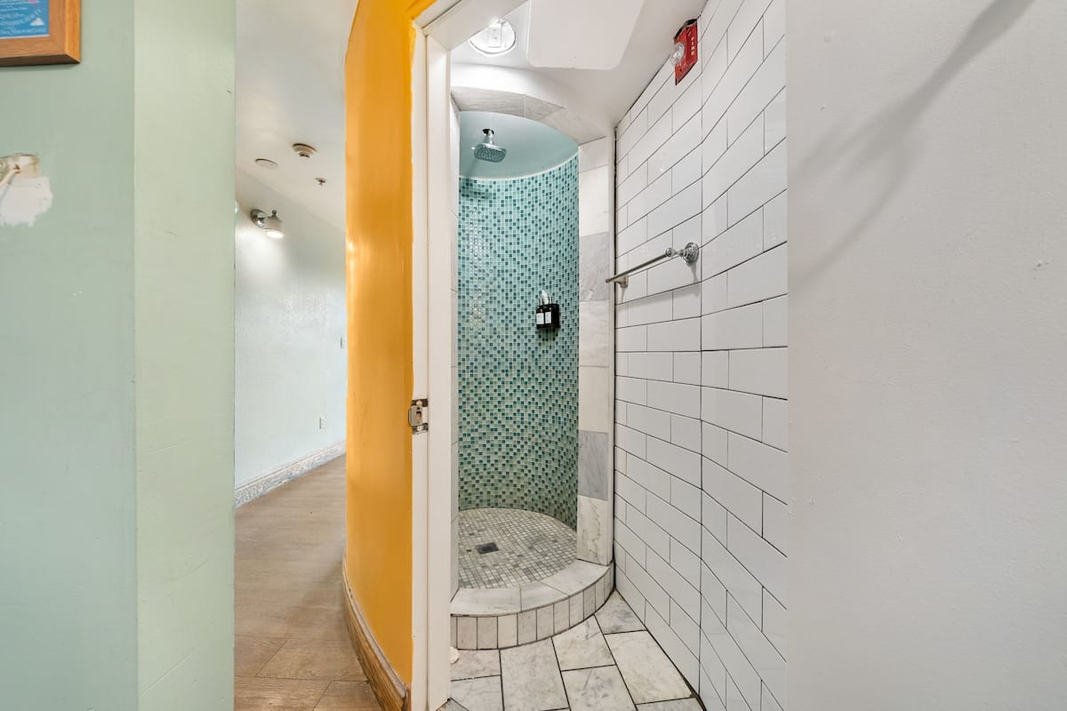 Un baño con ducha, paredes de azulejos y suelo de madera.